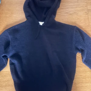 Svart stickad hoodie från Gina Tricot - Mysig svart stickad hoodie från Gina Tricot med huva och snörning. Perfekt för kyliga dagar och enkel att matcha med jeans eller mjukisbyxor. Långärmad och i en klassisk modell som funkar året runt.