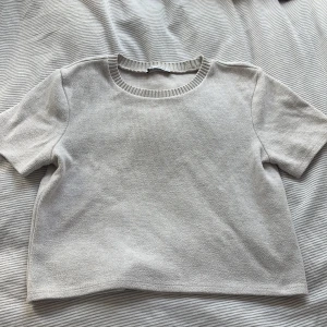 Beige stickad topp från Zara - Säljer en beige stickad topp från Zara med rund halsringning och korta ärmar. Toppen har en enkel och clean look med ribbad kant vid halsen. Toppen är i storlek M men är liten och kort så skulle säga att det är mer S eller XS.  Längd: 46cm, Bredd: 43cm