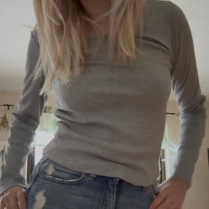 Grå ribbad långärmad tröja - Snygg grå långärmad tröja med ribbad struktur, perfekt att matcha med jeans eller kjol. Enkel och stilren design med rund hals, passar dig som gillar en clean look. Skön och mjuk känsla mot huden.