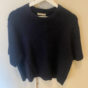 Mörkblå stickad tröja/ t shirt Gina Tricot - Mysig mörkblå stickad tröja från Gina Tricot med rund halsringning och kortare ärmar. Tröjan har en fluffig känsla och är perfekt för lager-på-lager under kyliga dagar. Enkel och stilren design som funkar till allt.