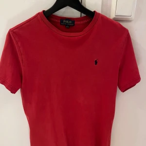 Röd t-shirt från Polo Ralph Lauren - Röd t-shirt från Polo Ralph Lauren med klassisk passform och korta ärmar. Ikoniska lilla broderade loggan på bröstet. Storleken är 14-16 år men passar Xs/S. Bara att höra av sig vid minsta fundering 