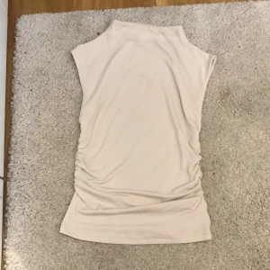 Krämvit tight tröja från hm - Tröjan har en lång/ish krage och är tight i midjan. Den har luftigt material 