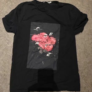 Svart t-shirt med rosor och tryck - Svart t-shirt med coolt tryck av röda rosor och texten 'CREATE' i glitch-stil på bröstet, från nakd. Storlek M. Säljer för 50kr