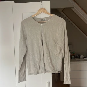 Beige kofta från Isolde, storlek L - En stilren beige kofta från Isolde i storlek L. Koftan har rund halsringning, knäppning framtill med matchande knappar och långa ärmar. Tillverkad i mjukt material som känns skönt mot huden. Perfekt att slänga över en t-shirt eller linne. Pris kan diskuteras 