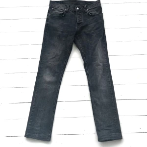 Svarta Nudie Jeans/ Grim Tim - Snygga grå svarta jeans från Nudie. Passformen är Grim Tim och storleken från börjar 32:34, men de är uppsydda till 32:32. Byxan är i ett mycket bra skick, tveka inte på att höra av dig vid minsta lilla fundering. Priset kan självklart diskuteras inom rimliga ramar😃