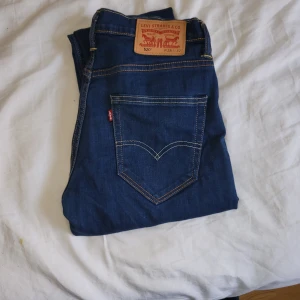 Levi's 520 blå jeans, W28 L32 - Säljer ett par Levi's 520 jeans i mörkblå tvätt med klassisk femficksdesign och kontrastsömmar. Modellen har rak passform och normal midja. Jeansen är tillverkade i slitstarkt denim med Levi's ikoniska läderpatch bak och röd etikett vid bakfickan. Mycket bra skick 