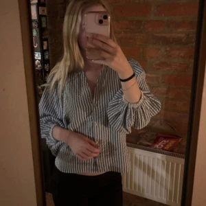 Randig blåvit skjorta från Lindex XS - Säljer en fräsch skjorta från Lindex i storlek XS med blå och vita vertikala ränder. Den har aldrig kommit till användning därav säljer jag den. 