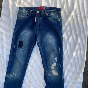 Dsquared2 blå slitna jeans - Snygga blå jeans från Dsquared2 med slitningar och patchdetalj på ena🌟🌟 jag har använt dom cirka 2 gånger dom är exklusiva och jag säljer dom för ändast 649