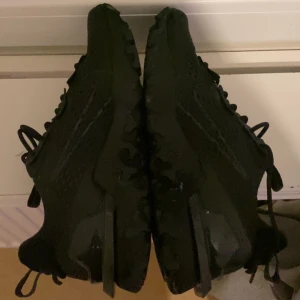 Nike react helsvarta sneakers - Säljer ett par helsvarta Nike Air Max 270 sneakers med chunky sula och snygg mesh-överdel. Skorna har snörning och en modern, sportig look som passar perfekt till streetwear. Ikonisk Air Max-dämpning i hälen för extra komfort.