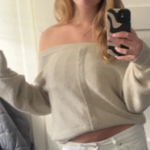 Beige offshoulder stickad tröja - Superfin beige stickad tröja med offshoulder-modell och avslappnad passform. Perfekt för dig som gillar en lite loose och trendig stil. Mjuk och skön, passar perfekt till jeans eller kjol.