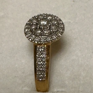 Guldring 18k med diamanter - Snygg ring i 18K guld med rund, glittrande topp täckt av små vita stenar. Ringen har stenar även längs bandet och en lyxig känsla. Storlek 17 1/2 och väger 2,4g. Perfekt för dig som gillar bling och vill sticka ut.