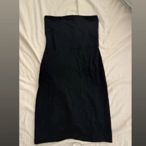 Svart axelbandslös klänning Zara - Snygg svart axelbandslös klänning från Zara i kort modell. Stilren och enkel design med figurnära passform som framhäver siluetten. Perfekt för dig som gillar minimalistisk stil och vill ha en klänning som känns både modern och klassisk.