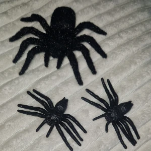 Dekorativa plastspindlar (3-pack) - Säljer ett set med tre dekorativa plastspindlar, perfekt för Halloween eller temafester. En större spindel med hårig yta och två mindre i hård plast. Alla i svart färg och i mycket gott skick, slitage eller defekter.