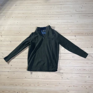Mörkgrön half zip tröja Dressmann L - Snygg mörkgrön långärmad tröja från Dressmann i storlek L. Tröjan har en praktisk half zip-dragkedja vid halsen och en diskret bröstficka. Materialet är mjukt och består av bomull och polyester med lite stretch för extra komfort. 
