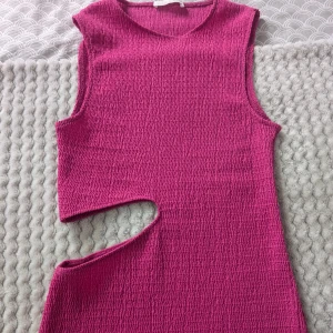 Rosa långklänning med cut-out Zara - Säljer en snygg rosa långklänning med cool cut-out detalj vid midjan. Klänningen är ärmlös och har en tight passform som framhäver figuren. Materialet är strukturerat och stretchigt, vilket gör den bekväm att bära. Perfekt för dig som vill sticka ut med en trendig look. Använd en gång. 