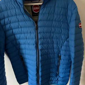 Blå Colmar pufferjacka strl 50 - Säljer en blå pufferjacka från Colmar i storlek 50 motsvarar ungefär S/m killen på bilden är 175 cm lång. Den är perfekt för både vår och höst och tidig vinter. Pris kan diskuteras skriv om eventuella frågor. 