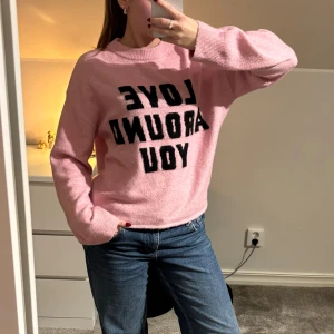 Rosa stickad tröja med text - Mysig rosa stickad tröja från H&M med svart texten 'LOVE AROUND YOU' framtill. Tröjan har rund halsringning, långa ärmar och en relaxed passform.  Super mjuk och skön i materialet!