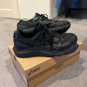 Svarta Asics Gel-Sonoma GTX 7 sneakers - Svarta Asics Gel-Sonoma sneakers med Gore-Tex för vattentäthet. Storlek 42,5. Skorna har mesh och syntetmaterial med robust sula. Använt då och då under cirka ett år men mina fötter har växt ur dem. Fortfarande i bra skick, enda deffekten är slitage på bakkanten av skorna som syns på bild 4. 