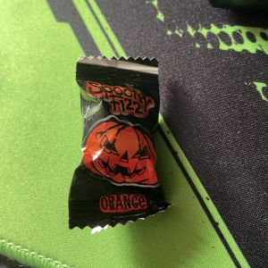 Spooky Fizzy Orange - Spooky Fizzy Orange är ett Halloween-inspirerat godis med en syrlig och kolsyrad smak. Förpackningen har en skrämmande pumpa och är oöppnad och i nyskick. Perfekt för godisskålen till Halloween eller som roligt tilltugg.