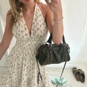 Vit blommig halterneckklänning - Supersöt kort vit klänning med små blommor i rosa och gult. Halterneck med knytning i nacken, djup v-ringning och smockad midja som ger en snygg siluett. Kjolen är lätt utställd och har volangkant. Perfekt för varma dagar och somriga vibes. Älskar denna klänning, så så fin! 💕