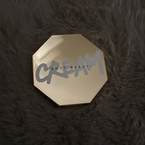 Fenty Beauty Cheeks Out Bronzer - Fenty Beauty Cheeks Out Freestyle Cream Bronzer i nyansen 02 Butta Biscuit. Kommer i en lyxig, åttakantig guldig dosa med spegel. Krämig formula i en ljusbrun ton som smälter in i huden för en naturlig look.