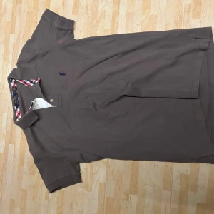 Mörkgrå pikétröja Polo Ralph Lauren - Säljer en brun pikétröja från Polo Ralph Lauren i storlek S. Tröjan har klassisk krage med snyggt rutigt mönster i rött, vitt och blått på insidan av kragen. Broderad logga på bröstet och korta ärmar. Tillverkad i mjuk bomull. Dock är det en liten fläck vid ärmen av pikén men det märks inte vid användning❗️ Nypris 1800kr mitt pris 400kr då den har en defekt, skicka gärna prisförslag och hör av er vid funderingar❗️❗️ Sällsynt och snygg piké från ralph lauren🙌🏼