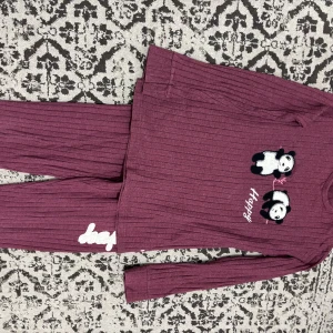 Mörklila ribbad långärmad tröja med pandor - Säljer en mörklila ribbad långärmad tröja med söta broderade pandor och texten 'happy' framtill. Tröjan har en avslappnad passform och är gjord i mjukt material som passar perfekt för mysiga dagar. Den har rund hals och ett gulligt, ungdomligt uttryck.