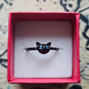 Svart ring med kattmotiv - Unik svart ring med en söt kattdesign framtill och glittrande blå ögon. Rostfritt stål, 16.9 mm