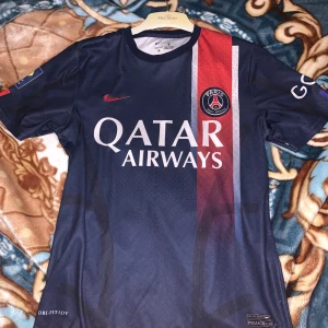 PSG Neymar Jr 10 matchtröja Nike S - Paris Saint-Germain fotbollströja med Neymar Jr och nummer 10 på ryggen. Tröjan är marinblå med röda och vita ränder framtill, PSG-logga på bröstet och Qatar Airways som sponsor. Tillverkad i Dri-FIT material för bästa komfort. Kortärmad och officiell Nike-produkt.
