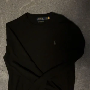 Merinoull polo Ralph lauren  - Svart långärmad tröja från Polo Ralph Lauren i tvättbar merinoull. Slim fit och passar perfekt för dig med storlek S/M stilren design som funkar till många olika looks. Hör av dig vid minsta funderingar!!!