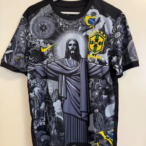 Brasil fotbollströja Nike svart/gul - Snygg Brasilien fotbollströja från Nike med unikt svart och grått grafiskt mönster, stora gula detaljer och nummer 10 på ryggen. Tryckt CBF-märke och Nike-logga på bröstet. Materialet är lätt och andas, perfekt för match eller träning.