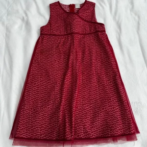 Röd klänning med hjärtmönster - Supersöt klänning med hjärtmönster och  omlott-detalj upptill. Har en liten fläck (se bild) men syns inte om man inte kollar noga. Fraktar inom 24h!