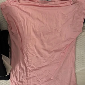 Ljusrosa topp från 157, storlek S - Enkel och stilren ljusrosa topp från 157 i storlek S. Toppen har en klassisk rak passform och är tillverkad i mjuk bomull, perfekt för en avslappnad look. Färgen är ljusrosa och materialet känns skönt mot huden.