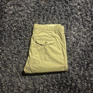 Beige Bowery chinos slim fit - Snygga beige chinos från Bowery i slim fit-modell. Byxorna har en bakficka med knapp och är tillverkade i mjuk bomull med lite stretch för extra komfort. Perfekta för en clean och stilren look.