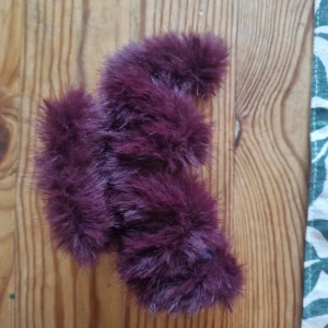 Vinröd fluffig fuskpäls-halsduk - Supermjuk och fluffig halsduk i vinröd fuskpäls. Perfekt accessoar för att ge din outfit en extra touch av lyx och värme. Halsduken är kortare i modellen och har en riktigt cool, trendig look.