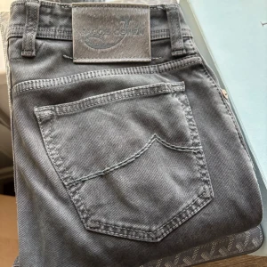 Jacob Cohen jeans - Snygga grå jeans från Jacob Cohen, modell 688 Comfort. Klassisk femficksdesign med silverfärgade knappar och broderad logga på myntfickan. Jeansen är tillverkade i mjuk bomull med en skön passform och stilren look. Största skadan är lite smuts som syns på sista bilden. Annars är dem fina.