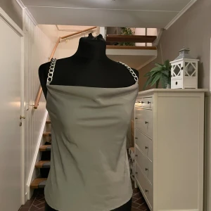 Grå linnetopp med kedjeaxelband - Snygg grå linnetopp, och coola silverfärgade kedjeaxelband. Perfekt för dig som vill festa!