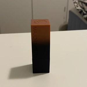 Major Mattes nude läppstift - Snyggt nude läppstift  Major Mattes med matt finish. Hylsan har en cool brun till svart ombre-design och själva läppstiftet är i en varm beige nyans. Perfekt för dig som gillar naturliga och trendiga läppar.