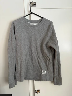 Grå sweatshirt från Resteröds - En basic grå sweatshirt från Resteröds med rund halsringning och långa ärmar. Tröjan har en liten vit patch nertill med logga och är gjord i mjuk bomullsmix. Perfekt för chill dagar eller när du vill ha en enkel och clean look.