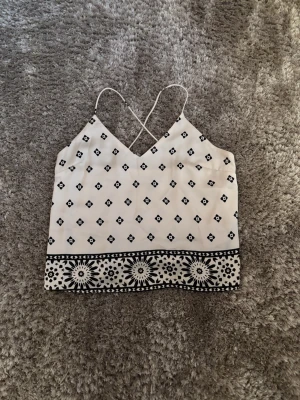 Vit och svart mönstrad linnetopp H&M - Säljer en vit linnetopp från H&M med tunna axelband som korsas i ryggen. Storlek M. Toppen är lite stor i storleken men har inga tecken för användning. Skriv för frågor eller fler bilder🤍