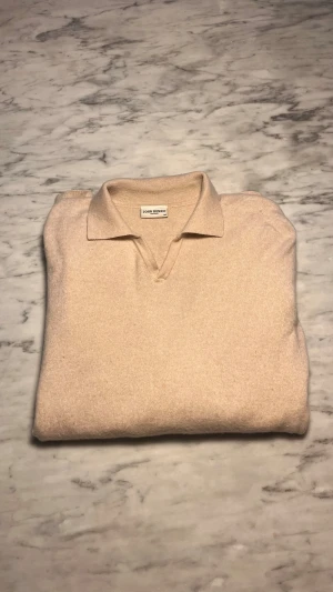 Beige pikétröja i ull/kashmir John Henric - Snygg beige pikétröja från John Henric i mjuk mix av 90% ull och 10% kashmir. Klassisk krage och v-ringad öppning framtill. Pris kan självklart diskuteras vid en snabb affär!