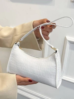 Vit axelväska  - Säljer en stilren vit axelväska med krokopräglat mönster. Väskan har en smal axelrem och guldfärgade metalldetaljer. Perfekt storlek för det viktigaste och ger en clean look till din outfit.