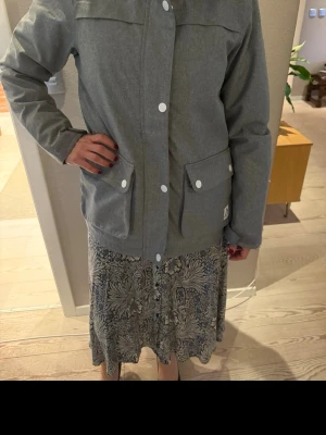 Grå skidjacka från WearColour - Snygg grå skidjacka från WearColour med huva och stora fickor framtill. Jackan har vita knappar och är unisex. 