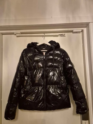 Svart pufferjacka från Guess, S - Säljer en glansig svart pufferjacka från Guess i storlek S. Jackan har huva med snörning, dragkedja framtill och stora fickor. Nypris 2000 och slutsåld överallt. Pris kan diskuteras💞