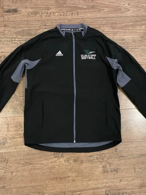 Adidas Vindjacka - Säljer en svart och grå vindjacka från Adidas med och är fodrad med mjuk fleece på insidan. Jackan är knappt använd och har inga skador på sig