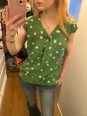 Grön prickig blus  - Grön blus med vita prickar utan ärmar.