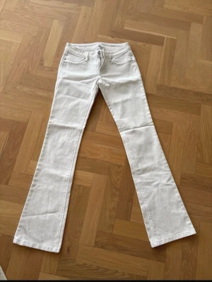 Vita bootcut jeans  - Säljer ett par vita jeans från DL1961, modell Cindy. De har bootcut-ben, klassiska fem fickor och snygga detaljer vid bakfickan. Jeansen är i stretchigt material för extra komfort och har låg midja. Perfekta till sneakers eller boots.