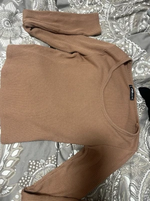 Ribbad brun långärmad tröja new Yorker  - Säljer en ribbad brun långärmad tröja från new Yorker . Tröjan har en rund halsringning och är i ett mjukt, stretchigt material som sitter snyggt på kroppen. Perfekt att styla med jeans eller kjol för en chill look.