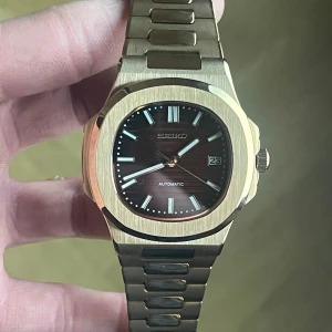 Seiko Mod Nautilus – Rose Gold (Brun Tavla) - ✨ Specifikationer Modell: Seiko Mod Nautilus Urverk: Automatiskt Seiko-urverk Gångreserv: 41 timmar ⏳ Boett: Rose gold-färgat rostfritt stål Storlek: 40 mm 📏 Glas: Reptåligt safirglas 💎 Urtavla: Brun horisontellt mönstrad tavla