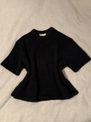 Svart stickad t-shirt  - Mysig svart stickad T-shirt från Gina Tricot. Tröjan har en enkel, clean look och är gjord i ett mjukt material som känns skönt mot huden. Perfekt till lager på lager under höst och vinter.💗